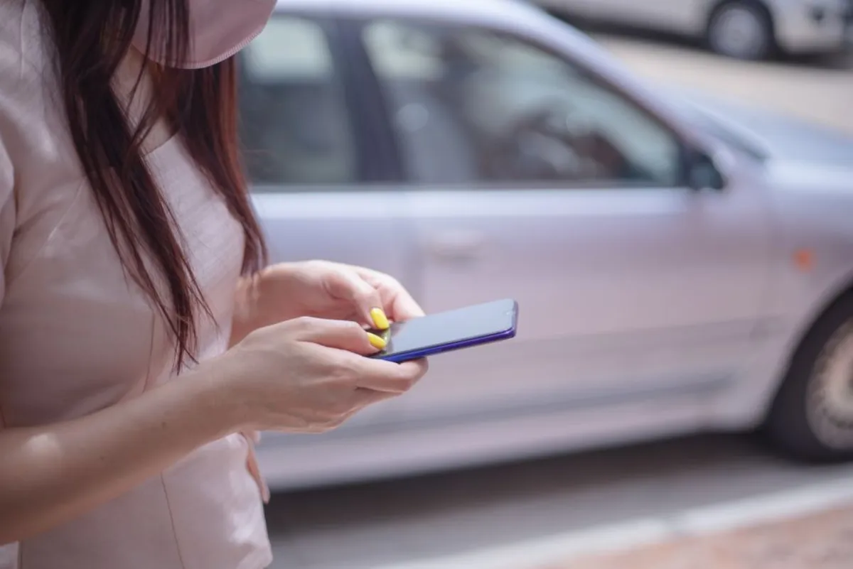 Conducteur déverrouillant sa voiture avec une clé de voiture sur smartphone